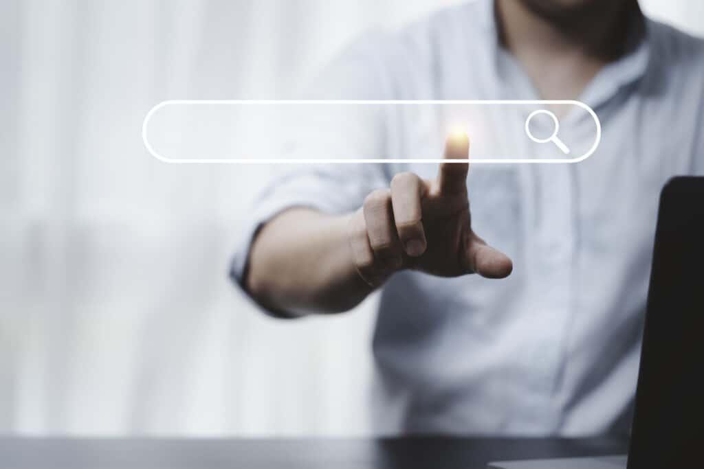 Une main posée sur l'icône de recherche pour l'optimisation pour les moteurs de recherche
